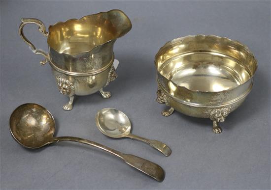 A George V silver cream jug and sugar bowl and a 19th century silver caddy spoon and sauce ladle.